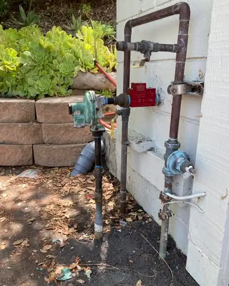 Outdoor piping and valves beside a house after a repair